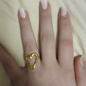 Säljer en superfin guldfärgad ring formad som ett hjärta. Den är perfekt för att ge en romantisk touch till din outfit. Ringen är i ett enkelt men elegant utförande och passar till både vardag och fest. Perfekt present till någon speciell eller till dig själv! 💛