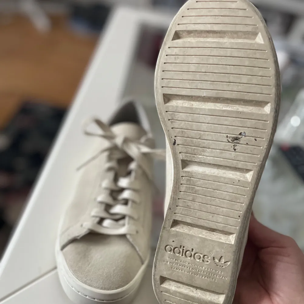 Säljer ett par stilrena beige sneakers från Adidas i bra skick. De har en klassisk design med snörning och en bekväm sula. Perfekta för vardagsbruk och passar till de flesta outfits. Skorna är använda men i bra skick, en liten fläck framtill på vänster sko samt lite på gummisulan. Herrskor men kan användas av dam. . Skor.