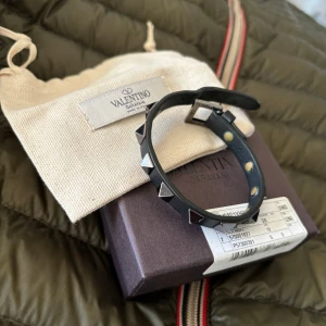 Valentino armband - Säljer mitt svarta armband från Valentino, mycoet bra skick, medföljer låda med påse samt extra nitar. Tveka inte att fråga vid funderingar!