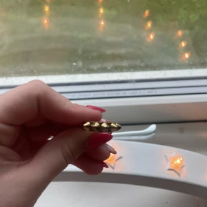 Guldfärgad ring med nitar - Säljer en cool guldfärgad ring med nitar. Den har en edgy stil och passar perfekt för att ge din outfit lite attityd. Ringen är i mycket bra skick och är en riktig statement piece. Perfekt för både vardag och fest!