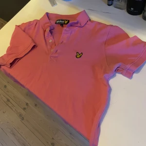 Rosa pikétröja från Lyle & Scott - Tröjan är i bra skick. Inga fläckar eller liknande. Ett jätte litet hål vid armen men syns knappt. Använd 5 gånger sedan bara varit i garderoben. Perfekt för både vardag och fest! Skriv om du har frågor!
