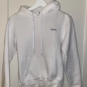 Vit hoodie med broderad text - Säljer en supermjuk vit hoodie med texten 'love' broderad på bröstet. Den har en klassisk känguruficka och justerbar huva. Perfekt för mysiga dagar eller en avslappnad stil. Passar till allt och är i bra skick! Den är i storlek XS. Pris kan diskuteras.