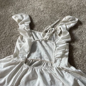 Vit topp  med volangdetaljer - Söt vit topp med volangdetaljer och knytband. Perfekt för sommaren. Använd en gång.