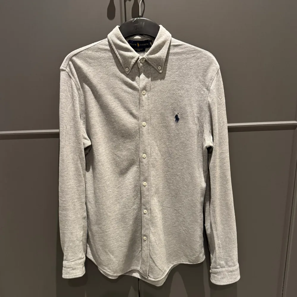 Säljer en snygg och stilren grå långärmad skjorta från Ralph Lauren. Den är i ett lätt och bekvämt material, perfekt för både vardag och fest. Skick: 7,5/10, inga skavanker. Nypris: ca 1500kr. För fler frågor, kontakta! 😁👔. Skjortor.