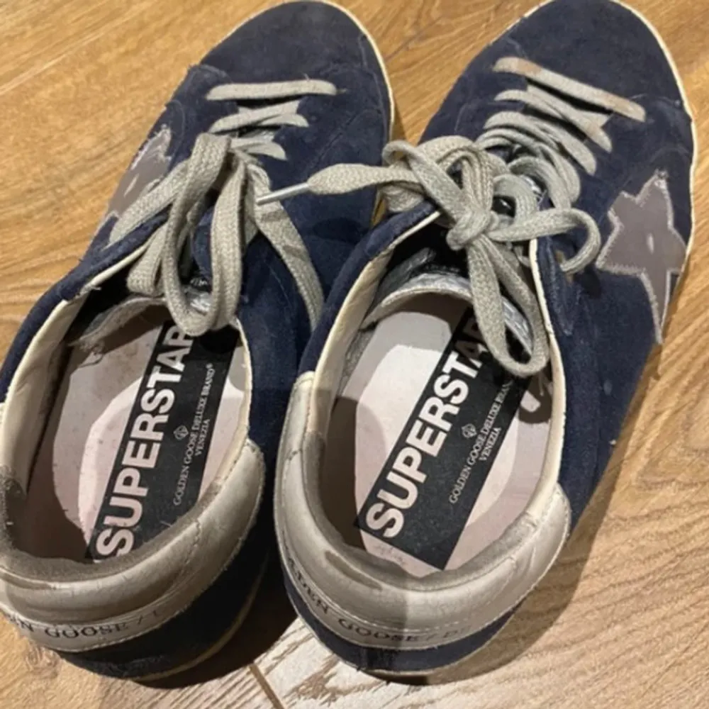 Säljer ett par snygga blå sneakers från Golden Goose i bra skick. De har en cool stjärndetalj på sidan och grå snörning. Perfekta för en avslappnad stil och passar till både jeans och shorts. Skorna har en bekväm passform och är idealiska för vardagsbruk.. Skor.