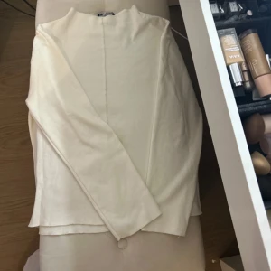 Vit långärmad tröja från Zara - Säljer en vit långärmad tröja från Zara. Tröjan har en enkel design med en liten krage och är tillverkad i ett ribbat material. Perfekt för en stilren look. Den har en liten fläck men inget som syns jätte tydligt. köpt för 500kr och använd ett fåtal gånger
