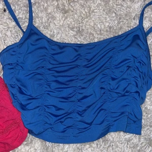 Blå och rosa linnetopp - Två snygga linnen i blått och rosa. Den blå toppen har smala axelband och rynkade detaljer, perfekt för en somrig look. Den rosa toppen har knytband och volangdetaljer, vilket ger en romantisk touch.