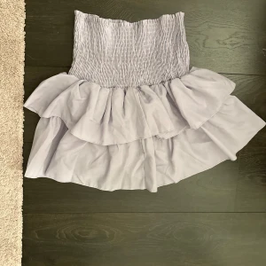 Ljuslila volangkjol - Säljer en söt ljuslila kjol med volanger. Kjolen har en elastisk midja som ger en bekväm passform. Perfekt för en somrig look!