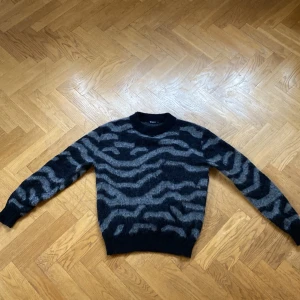 Grå och svart tröja från Tiger of Sweden - Snygg tröja från Tiger of Sweden i grått och svart med ett coolt zebramönster. Nyskick och väldigt skön att ha på sig. Priset är inte hugget i sten så kom med bud!