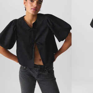 Svart blus från Gina Tricot - Snygg svart blus från Gina Tricot med puffiga kortärmar och knytning framtill. Perfekt för festliga tillfällen men även till vardags.