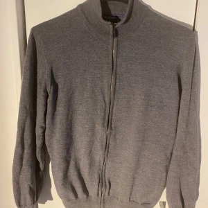 Grå kofta med dragkedja - Säljer en stilren grå kofta från SAND Copenhagen. Perfekt för kyligare dagar. Mjuk och skön, 100 % merinoull. Finns en liten defekt se bild 3, bör gå bort med rätt medel. Nypris ca 200 euro = 2400 kr. Mitt pris endast 499. Passar S/XS. Ställ gärna frågor!🙏