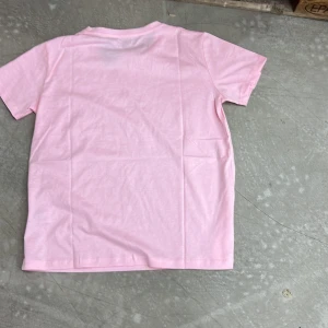 Rosa t-shirt - Säljer en enkel och stilren rosa t-shirt. Perfekt för en avslappnad look. T-shirten har korta ärmar och är gjord i ett mjukt material.