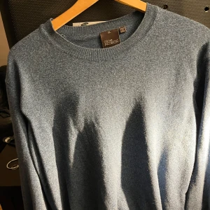 Blåmelerad tröja från Oscar Jacobson - Säljer en stilren blåmelerad tröja från Oscar Jacobson, tillverkad i Italien. Tröjan har en klassisk design med rund hals och långa ärmar. Perfekt för en elegant och avslappnad look. Storleken känns mer som stor L. Finns bilder med den på vid förfrågan!