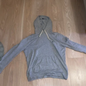 Grå hoodie från Polo Ralph Lauren - Säljer en stilren grå hoodie från Polo Ralph Lauren. Den har en klassisk design med känguruficka och justerbar huva med snören. Perfekt för en avslappnad look. Passar perfekt om du är 175-180cm! Har användt den 1 gång