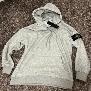 Stone island hoodie - Säljer nu en riktigt fin rep stone island hoodie i grå färg. Hoodien är i storlek M och är i nyskick. Sjukt skönt material på både ut och insidan. Bara att skriva ifall det finns några funderingar!