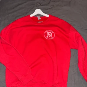 Röd sweatshirt med tryck - Säljer en röd sweatshirt med ett unikt tryck av en bläckfisk på baksidan och en logotyp på framsidan. Tröjan har långa ärmar och rund halsringning. Perfekt för en avslappnad stil. (GILDAN) Vid snabbt köp kan priset diskuteras!☺️