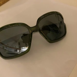 Gröna solglasögon med breda bågar - Snygga gröna solglasögon med breda bågar och mörka linser. Perfekta för att ge en cool touch till din stil. De har en klassisk form som passar de flesta ansikten.