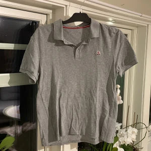 Grå pikétröja från Moncler - Säljer en stilren grå pikétröja från Moncler som är köpt på plick och vet därför inte om den är äkta(därför priset är så lågt). Skick 8/10 tveka inte att skriva om ni har några funderingar! Pris 499kr