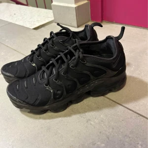  Nike Vapormax plus - Säljer ett par svarta Nike Vapormax sneakers med en futuristisk design och synlig luftdämpning i sulan. Skorna har snörning och en stilren look som passar perfekt för en modern stil. Pris kan diskuteras 😄