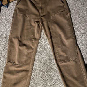 Bruna Carpenter Pants - De är knappast använda, har inget slitage. De är från Zara och är ungefär 32 i midja. Passar perfekt till streetwear stil. Tveka inte att höra av er om ni har frågor!