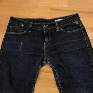 Mörka low waist bootcut jeans från Replay - Skitsnygga lågmidjade bootcut jeans från Replay!! Thriftade skinny jeans som jag sytt bootcut själv, och lagt ner sömnen längst ner för att göra längre. Loggan på baksidan hade slitits av något, som jag har sytt fast, se bild. Storleken på etiketten är W28 L32. Mått: midja tvärs över: ca 37,5.  Innerbenslängd: ca 79cm