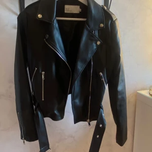 Svart skinnjacka  - Snygg svart skinnjacka från Nelly med dragkedjor och bälte. Andvänd fåtal gånger så mycket fint skick