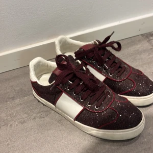 Valentino fly crew  - Snygga vinröda sneakers från Valentino med glittrig yta och vita detaljer. Skorna har snörning och nitar på hälen för en extra touch. Perfekta för att ge din outfit lite extra bling! Skick 9,7/10 nästan helt nya snygga velentino flycrew