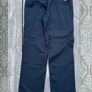 Dickies Original Work Slim Straight Mörkblå - Snygga mörkblå byxor från Dickies i modellen Slim Straight. De har en klassisk design med dragkedja och knapp framtill. 
