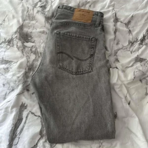 Gråa jack and Jones jeans - Snygga grå jeansbyxor i loose fit-modell från märket jack and jones. De har en klassisk femficksdesign och en bekväm passform. Perfekta för en avslappnad stil.