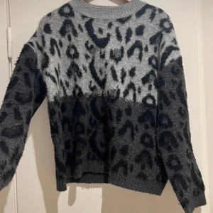 Grå och svart leopardmönstrad tröja - Säljer en cool grå och svart tröja med leopardmönster. Tröjan har långa ärmar och en avslappnad passform. Perfekt för att ge din outfit en trendig touch.❤️
