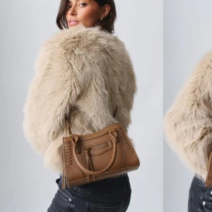 Brun handväska - Väska i läderimitation med handtag upptill. Väskan är brun och har metalldetaljer. Den har lång, reglerbar axelrem och stängning med dragkedja. 