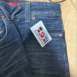 Blå flare jeans från Denim Demon - Snygga blå jeans från Denim Demon med klassisk femficksdesign och en bekväm passform. Jeansen har en diskret tvättad look och en läderpatch med logotyp på baksidan. Perfekta för en avslappnad stil.