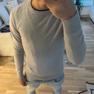 Grå tröja från Gran Sasso - Snygg och stilren grå tröja från Gran Sasso. Perfekt för en avslappnad men ändå elegant look. Tröjan har långa ärmar och en rund halsringning, vilket gör den lätt att matcha med olika outfits.