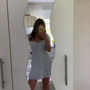 Blommig klänning från Hollister - Söt blommig klänning från Hollister i ljusblått och vitt. Den har korta puffärmar och en bra passform med resår i midjan. Ärmarna kan både has som på bilden men även off shoulder. Perfekt sommarklänning! Nästan som ny då den ändats är använd ett fåtal gånger 🌸