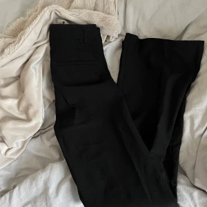 Svarta kostymbyxor - Snygga svarta kostymbyxor med en elegant och stilren design. Byxorna har en rak passform och är perfekta för en formell look. De är tillverkade i ett mjukt och bekvämt material som ger en skön känsla hela dagen.