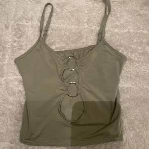 Grön croppad linnetopp - Snygg grön croppad linnetopp med unika utskärningar framtill. Toppen har smala axelband och en tight passform