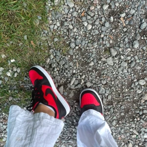 Nike Jordans i rött och svart - Snygga Nike Jordans i en iögonfallande röd och svart färgkombination. Skorna har en klassisk design med snörning och en vit sula som kontrasterar snyggt mot det röda och svarta. Perfekta för både stil och komfort.