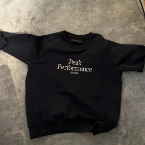 Svart tröja från Peak Performance - Säljer en stilren svart tröja från Peak Performance med vit text på bröstet. Använd max 2 gånger inprensip helt ny.  