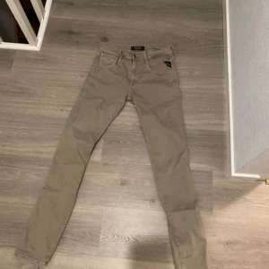 Beige Replay Anbass jeans - Snygga beige jeans från Replay, modell Anbass. De har en klassisk femficksdesign och är tillverkade i ett bekvämt material. Perfekta för en stilren look.
