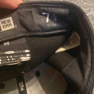 Svart keps från New Era - Snygg svart keps från New Era i storlek 7 1/4 (57.7 cm). Kepsen har en broderad logga på sidan och MLB-logga baktill. Perfekt för en stilren look. Klistermärket är lite suddigt, kan ta bort om man vill. 