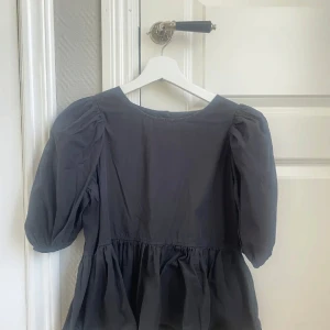 Mörkgrå blus med puffärmar - Säljer en stilren mörkgrå blus med puffiga trekvartsärmar och en lätt rynkad nederdel. Passar bra till både jeans och kjol.