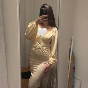 Champagnefärgad/beige klänning med ringdetalj - Elegant champagne/beige färgad figurnära klänning med en unik ringdetalj i midjan. Har även scrunch på bakdelen som ger en väldigt fin och smickrande look✨Helt oanvänd 