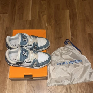 Blå och vita sneakers från Louis Vuitton - Snygga sneakers från Louis Vuitton i blått och vitt med märkets logotyp på tungan och hälen. Skorna har en stilren design med snörning och kommer med originalförpackning och dustbag.