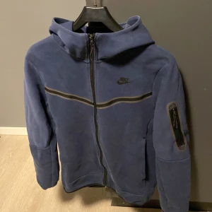 Nike Tröja - Tech fleece som är blå, den är både skön och snygg. Lite sliten men inte så mycket.