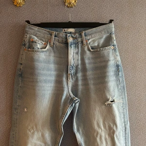 Ljusa jeans från Gina Tricot - Snygga ljusa jeans från Gina Tricot Perfect Jeans med slitningar på framsidan. De har en klassisk femficksdesign och knappgylf. Perfekta för en avslappnad stil. Har även en slots på benen.