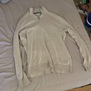 Jack and Jones half zip - Säljer en stilren beige tröja från Jack & Jones med dragkedja vid halsen. Tröjan har långa ärmar och ribbade muddar vid ärmslut och nederkant. Perfekt för en avslappnad look.