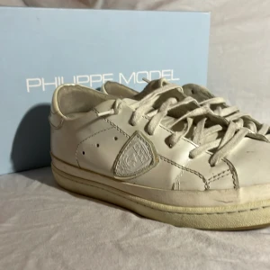 Vita sneakers från Philippe Model - Snygga vita sneakers från Philippe Model med klassisk design och snörning. Skorna har en diskret logga på sidan och en bekväm sula. Perfekta för en stilren look.