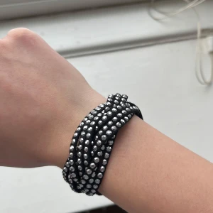 Svart armband med silverdetaljer - Snyggt svart armband med flera rader av glittriga silverpärlor. Det är som en fläta och knäpps för att stängas(som man ser på andra bilden) Väldigt snygg men används inte jättemycket så säljs därför💕👍🏼