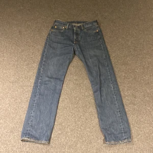 Levis 501 jeans - Klassiska Levis 501 jeans i blå denim. De har en rak passform, de är storlek 30-32. Och anledningen till att det inte är någon Levis text på tagen på bakfickan är för att på var 50onde par jeans de tillverkar måste dem lämna den tom för att de ska få behålla sin trademark. Köpta på carlings andvända ca 2 gånger
