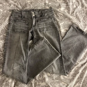 Lågmidjade gråa jeans från Gina Tricot - Superfina ljusgrå lågmidjade utsvängda jeans från Gina Tricot. Stretchiga material och använda enstaka gång. Midjemått: 37cm. Innerbenlängd: 78cm. Skriv för fler frågor eller bilder💗